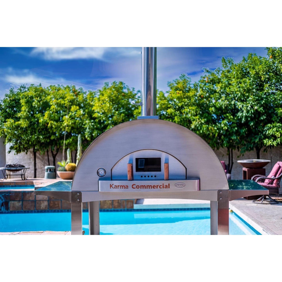 WPPO Karma 55-inch commercial wood-fired pizza oven in a backyard poolside setting with stainless steel chimney