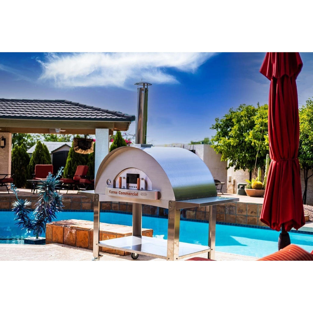 WPPO Karma 55-inch commercial wood-fired pizza oven on a stainless steel cart beside a backyard pool