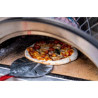 Pizza being removed from a WPPO Karma wood-fired pizza oven with a pizza peel