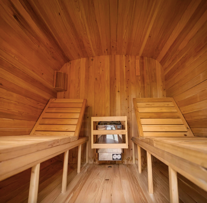 ALEKO Arnica 6-Person Rustic Cedar Outdoor Sauna interior showing dual adjustable benches, cedar walls, ventilation, and centrally mounted Harvia heater