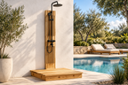 Cedar outdoor shower with black rainfall showerhead and handheld sprayer installed beside a swimming pool and lounge area.