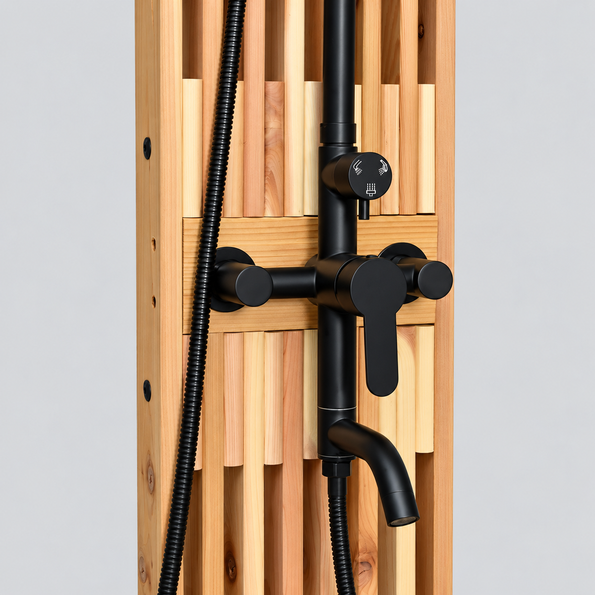 Close-up of matte black outdoor shower controls, diverter, and lower spout mounted on a cedar slatted panel.
