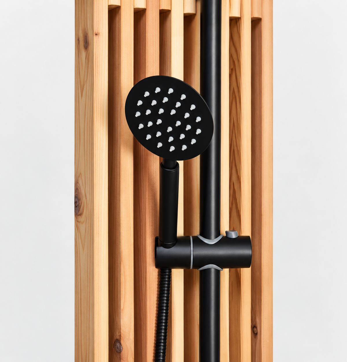 Matte black handheld shower sprayer with flexible hose mounted on a cedar slatted outdoor shower panel.