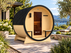 ALEKO Celasia 2–4 Person Outdoor Barrel Sauna with front porch canopy in a landscaped backyard wellness setting