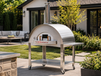 WPPO Karma 55-inch commercial wood-fired pizza oven on a stainless steel mobile cart in a modern backyard patio setting