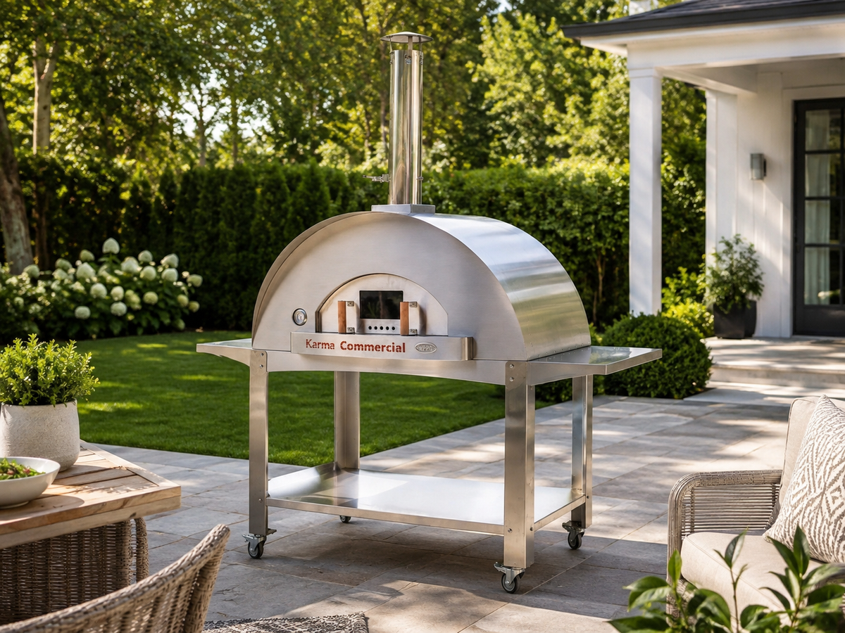 WPPO Karma 55-inch commercial wood-fired pizza oven on a stainless steel mobile cart in a backyard patio setting