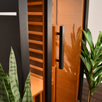 Close-up of the ALEKO Oasis 1-Person Infrared Sauna showing the glass door, black exterior, and warm Canadian hemlock interior