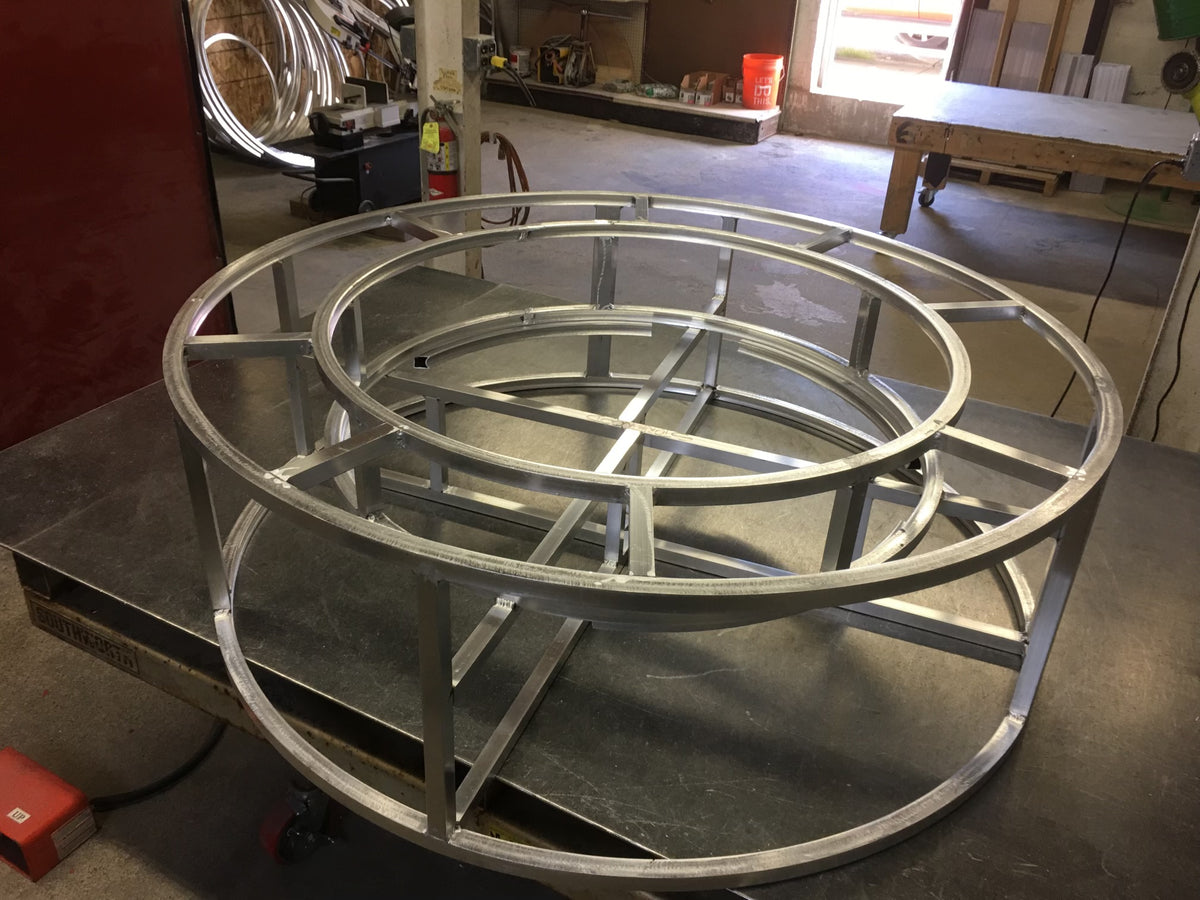 EZ Finish Firefly 48-inch round fire pit welded aluminum frame shown during fabrication in a workshop.